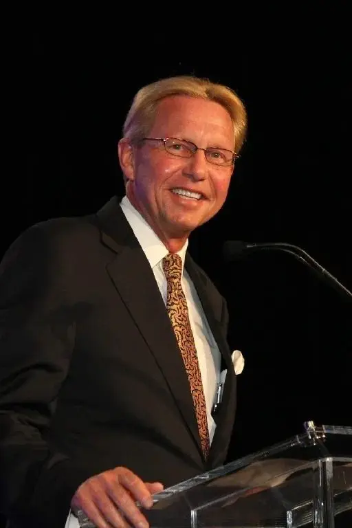 Man in suit speaking at a podium.