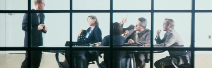 Business meeting in a glass-walled conference room.