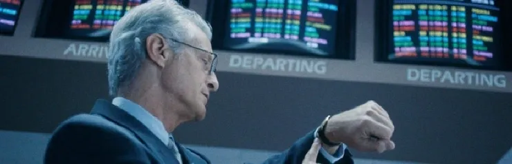 Man checking watch at airport departure board.